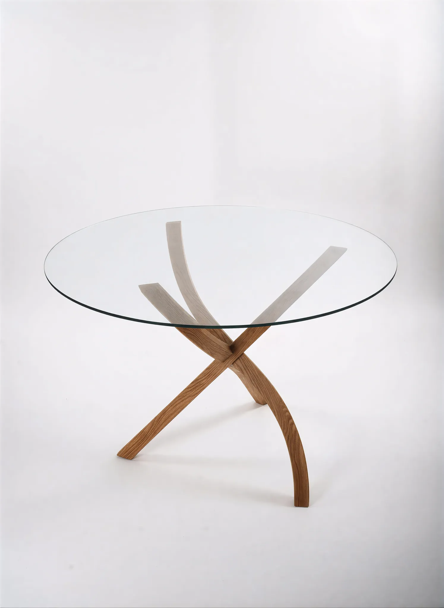 Round glass-top table with sculpted solid-oak legs